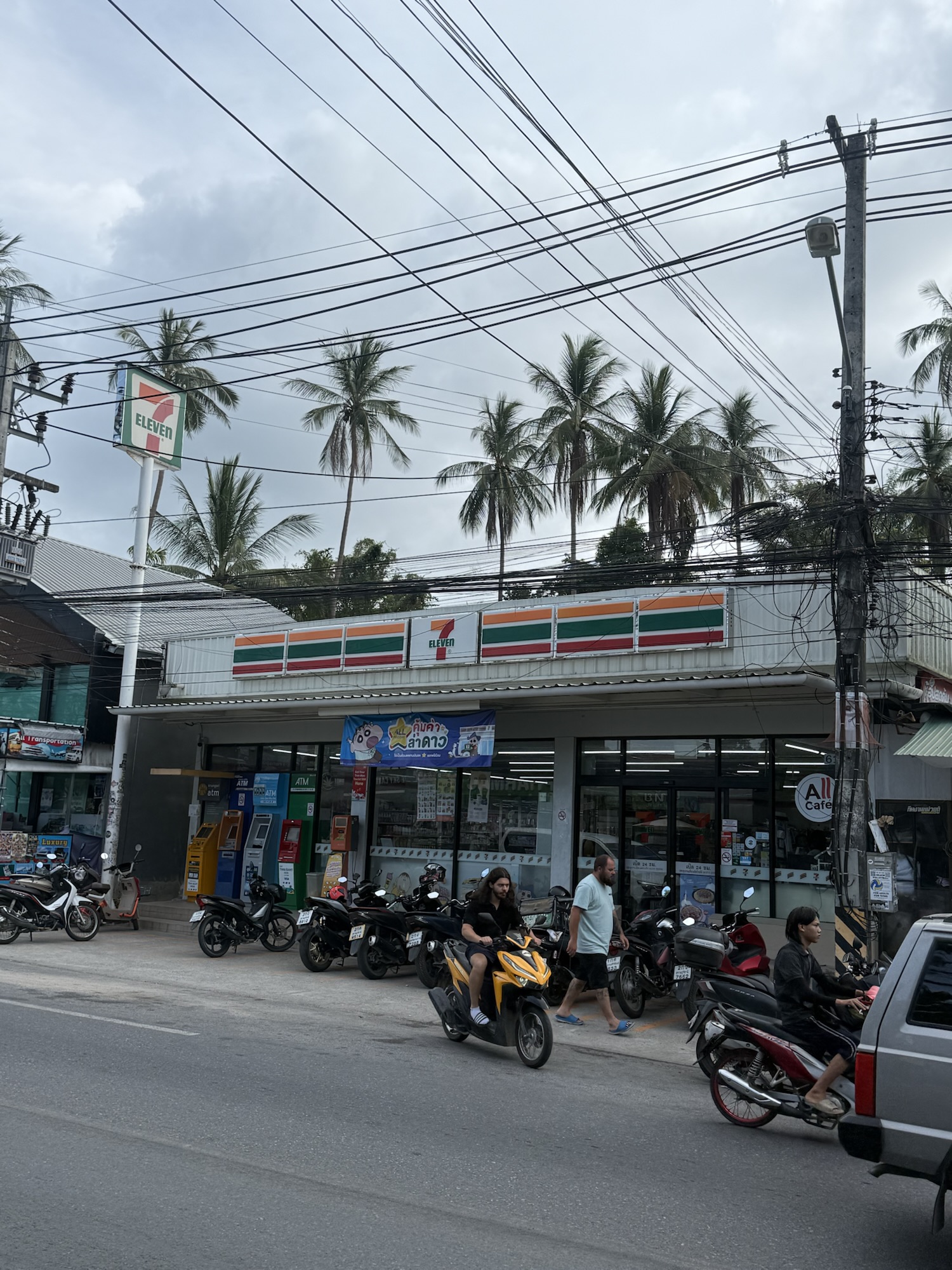 ホテル前の通りにあるセブンイレブンとバイクが並ぶローカルな街並み