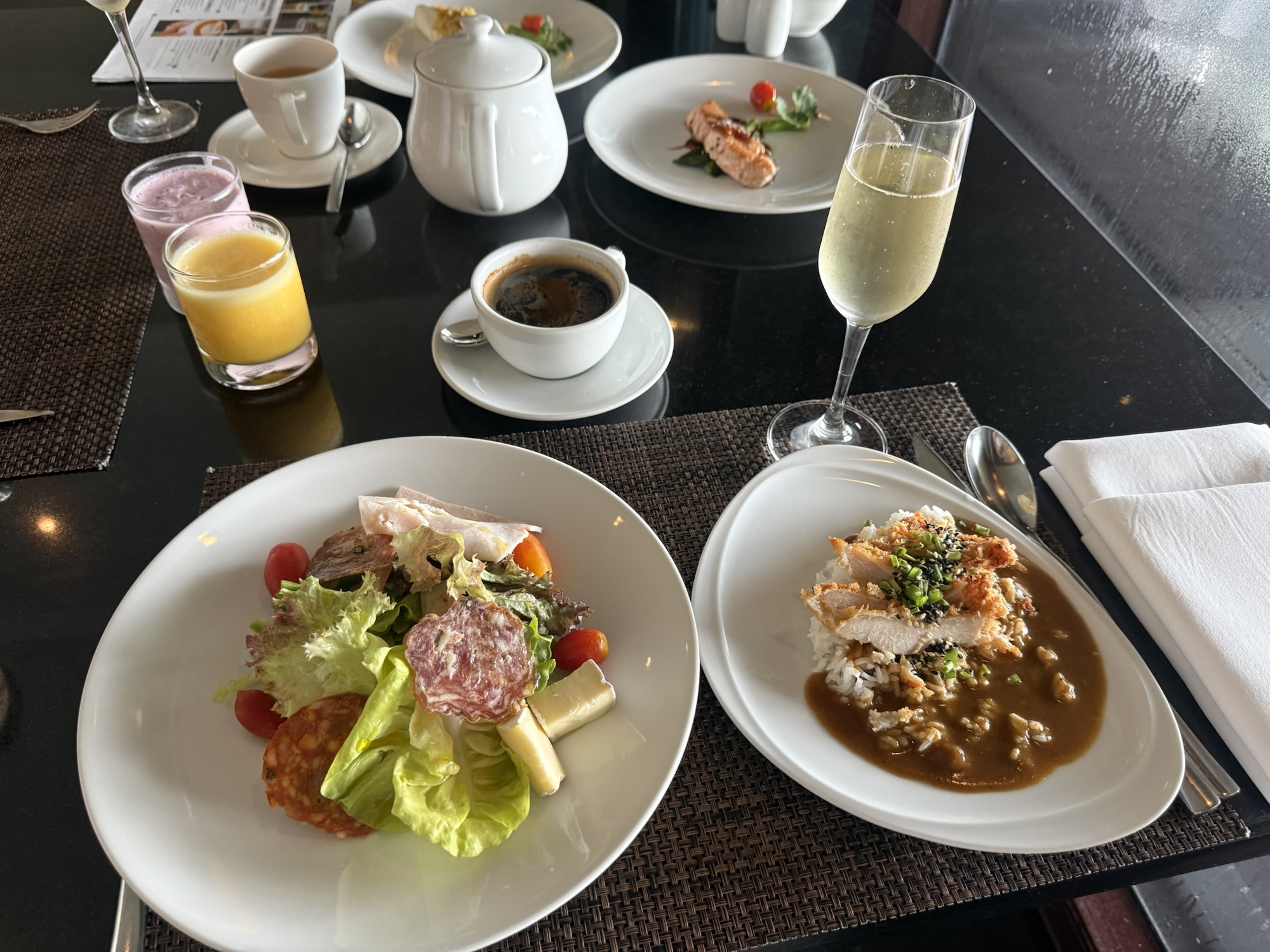 サラダプレートとカツカレー、スパークリングワイン、コーヒー、ジュースを並べた朝食