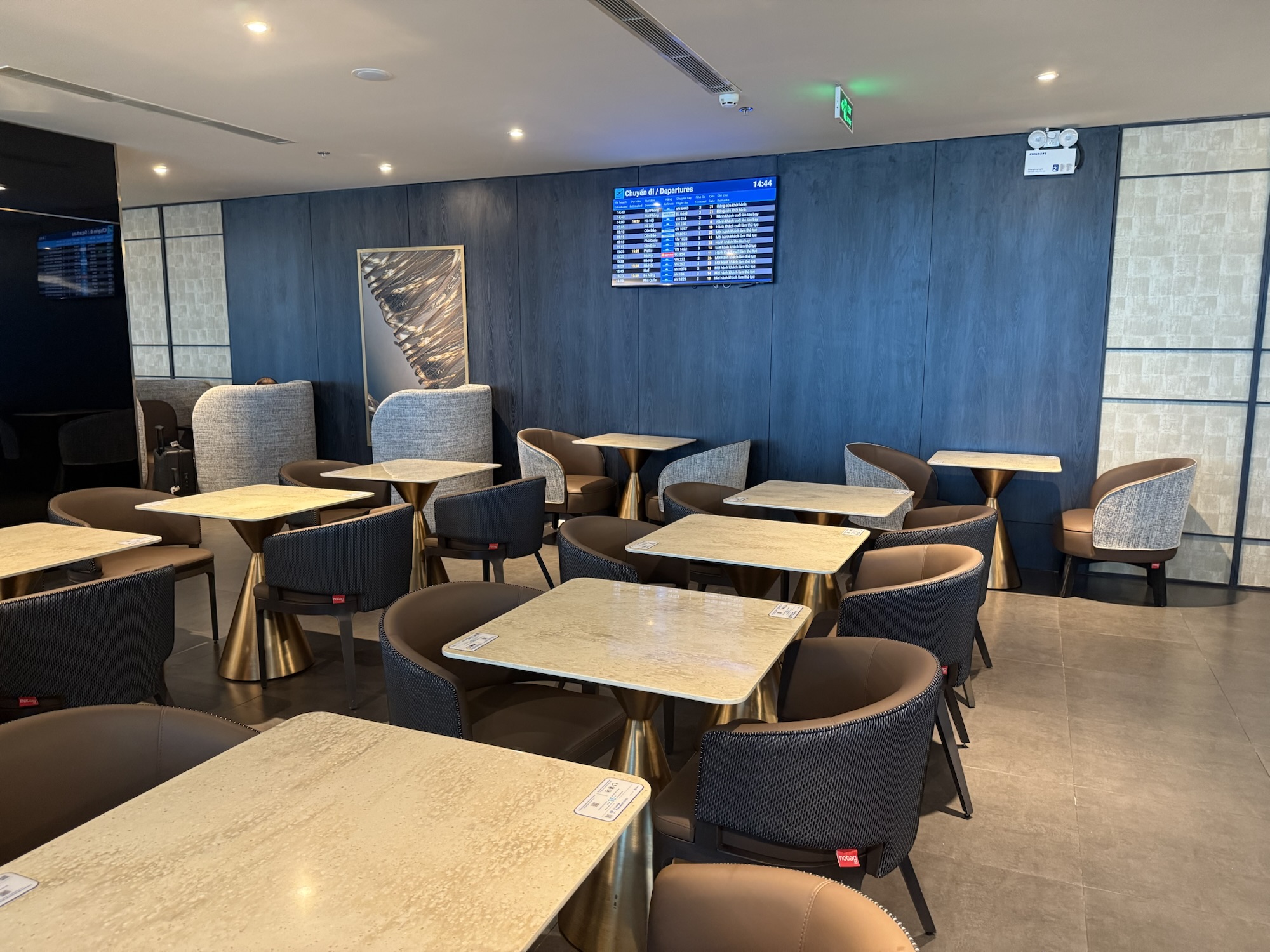 The SENS Business Loungeのテーブル席とフライト情報モニター