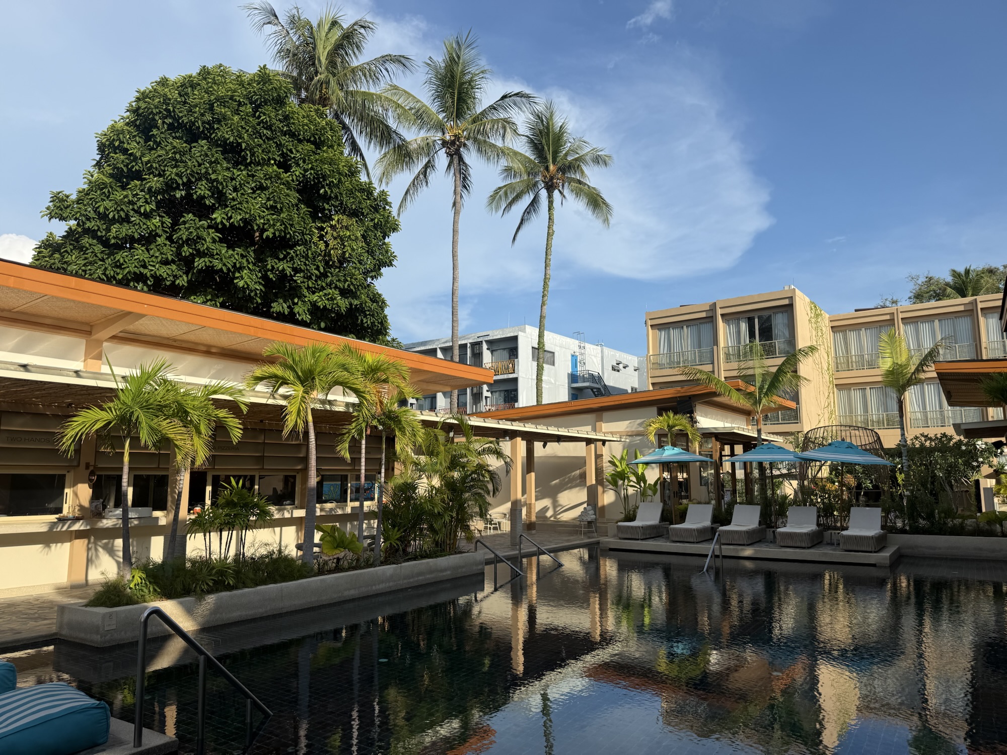 ヤシの木に囲まれたMarasca Samuiのプールと低層の客室棟